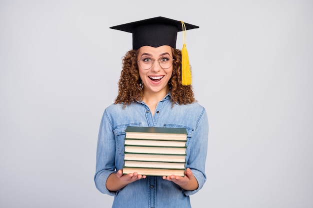 vrouw met gediplomeerde hoed en stapel boeken