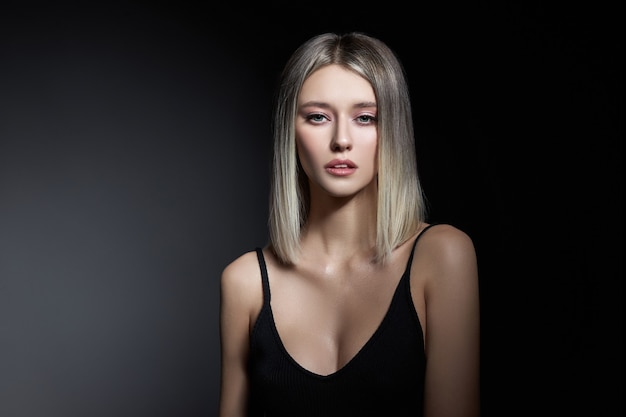 Vrouw met gekleurde haarkleur van een blonde op zwarte achtergrond. Kleur haar vrouw model in ash kleur