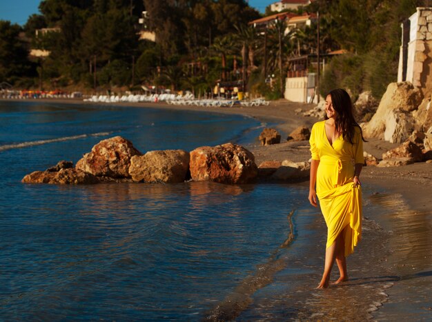 Vrouw met gele jurk op een strand.