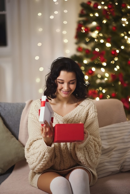 Vrouw met geschenkdoos in de buurt van kerstboom thuis