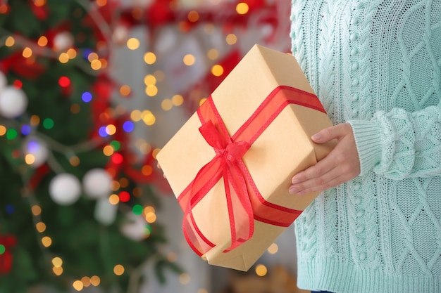 Vrouw met geschenkdoos tegen wazige kerstverlichting