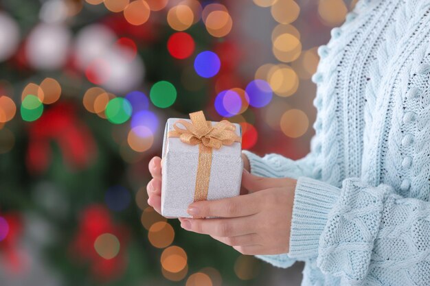 Vrouw met geschenkdoos tegen wazige kerstverlichting