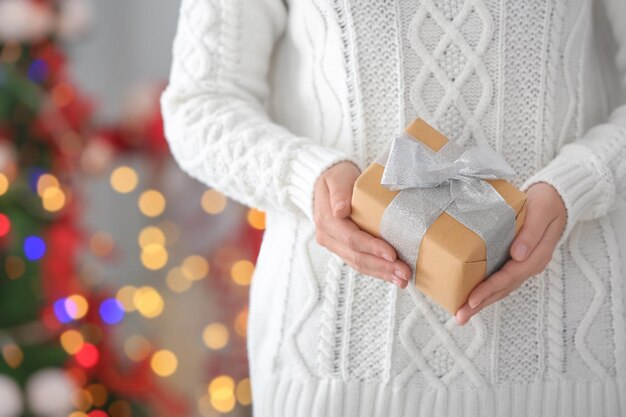 Vrouw met geschenkdoos tegen wazige kerstverlichting