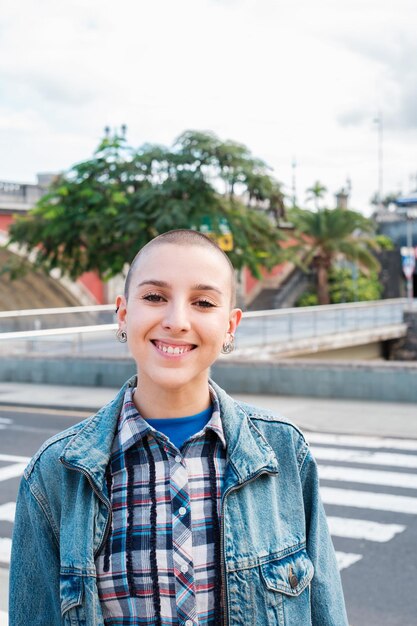 Vrouw met geschoren haar lachend met de stad op de achtergrond concept lifestyle feminisme stad