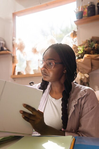 Vrouw met gevlochten haar op haar kantoor die door de documenten kijkt