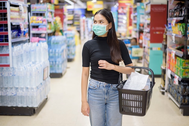 Vrouw met gezichtsmasker is winkelen kleding in winkelcentrum