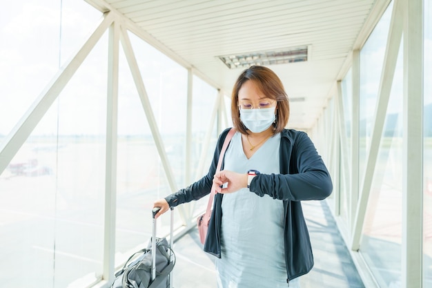 Vrouw met gezichtsmasker reist op de luchthaven, nieuwe levensstijlreizen na covid-19. Sociaal afstand nemen en reizen zeepbel concept.