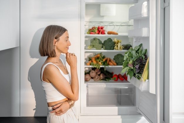 Foto vrouw met gezonde groenten in de koelkast