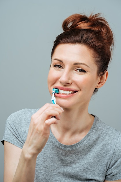 Vrouw met gezonde witte tanden houdt een tandenborstel vast en glimlacht mondhygiëneconcept