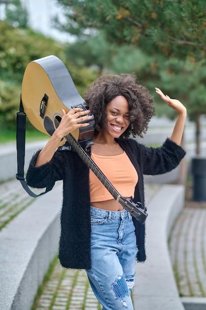 Vrouw met gitaar op schouder kijken naar camera