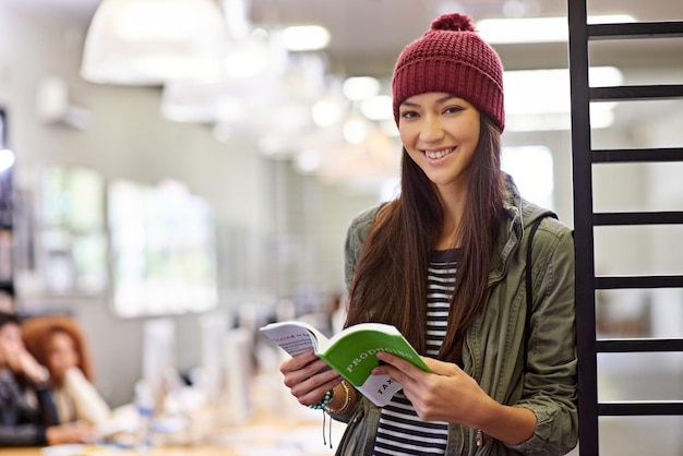 Vrouw met glimlach in portret student in bibliotheek leesboek en studeer voor examen op universiteitscampus Onderwijs leren en academische ontwikkeling met vrouwelijke persoon die leerboek vasthoudt voor kennis