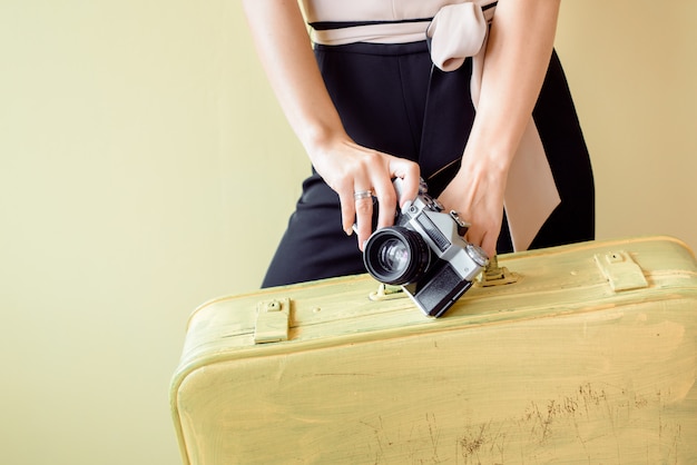 Vrouw met grote bagage loopt naar de luchthaven. Hete vakantie, reizen naar warme landen aan zee. meisje met grote gele koffers op een gele achtergrond, met strooien hoed, tropische elegante vrouw