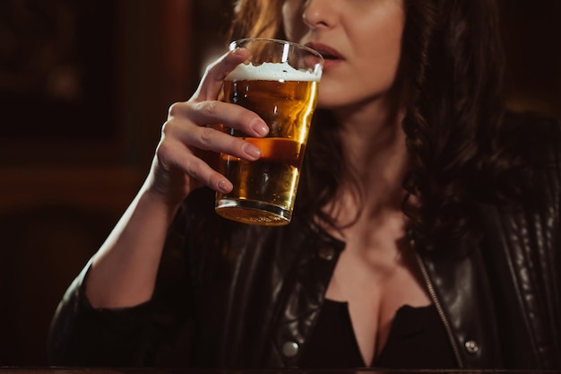 Vrouw met grote borsten drinkt seksueel pilsbier met schuim uit een glas