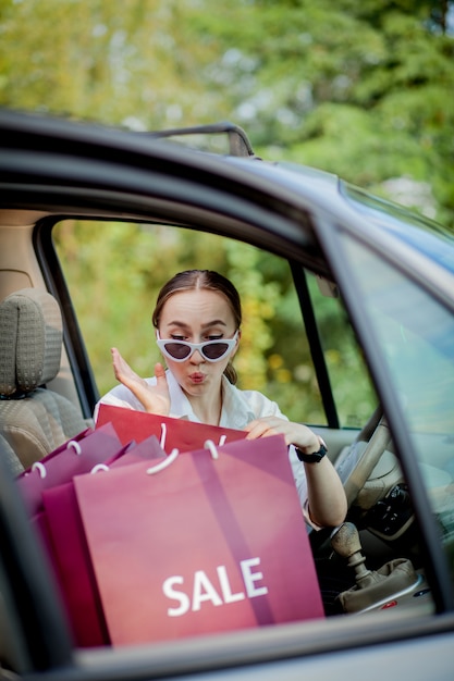 Vrouw met haar boodschappentassen in de auto - winkelen concept.