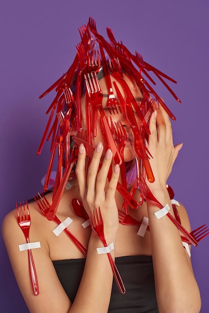 Foto vrouw met haar gezicht bedekt met plastic vorken en lepels