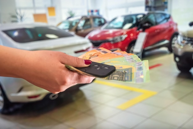 Vrouw met haar hand een grote hoeveelheid nieuwe eurobankbiljetten in de autoshowroom. Bedrijfsconcept. Auto interieurconcept