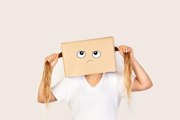 Vrouw met haar hoofd in een lelijk gebaar van een doos en haar eigen staartjes trekkend op een witte achtergrond