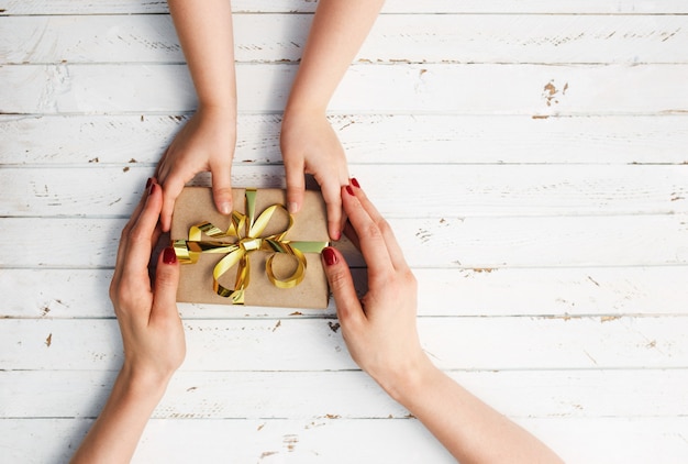 Vrouw met haar kind een geschenk in de hand houden op witte houten achtergrond.