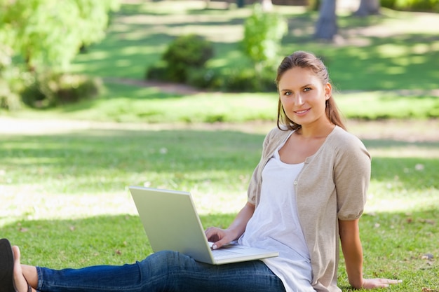 Foto vrouw met haar laptop zittend op het gazon