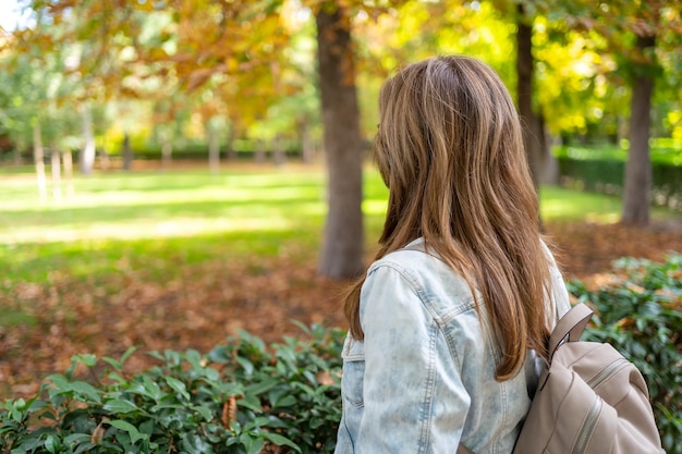 Vrouw met haar rug kijkend naar het landschap op een mooie herfstdag met gouden zonlicht