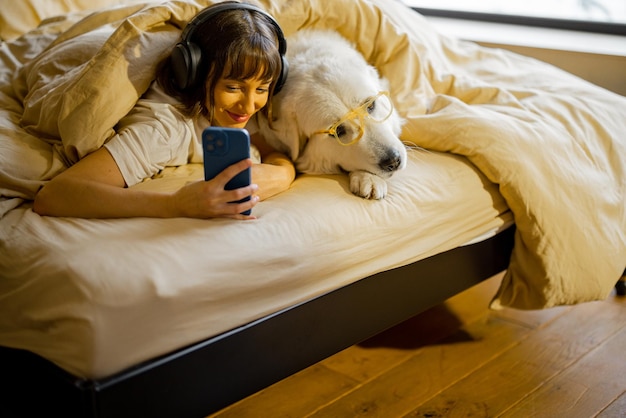 Vrouw met haar schattige hond met behulp van telefoon in bed