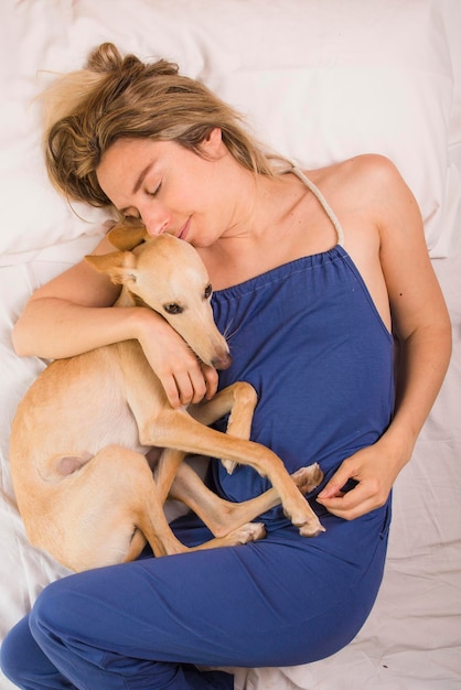 Vrouw met haar windhondhond in wit bed