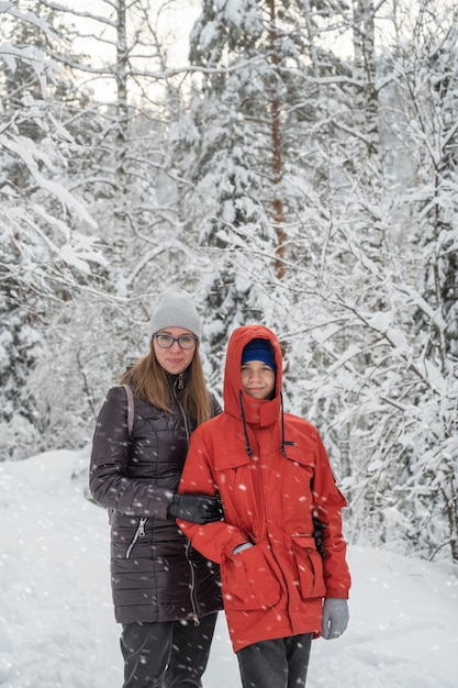 Vrouw met haar zoon wandelen in besneeuwde winterbos besneeuwde winterdag