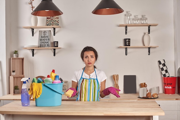 Vrouw met handschoenen aan met een spons in zijn handen kom vol flessen met ontsmettingsmiddel op tafel