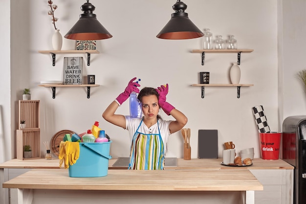 Vrouw met handschoenen aan met een spons in zijn handen kom vol flessen met ontsmettingsmiddel op tafel