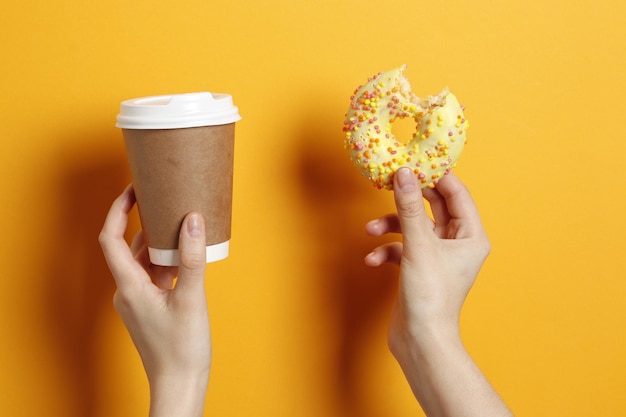 Vrouw met heerlijke donut en koffie op kleur achtergrond