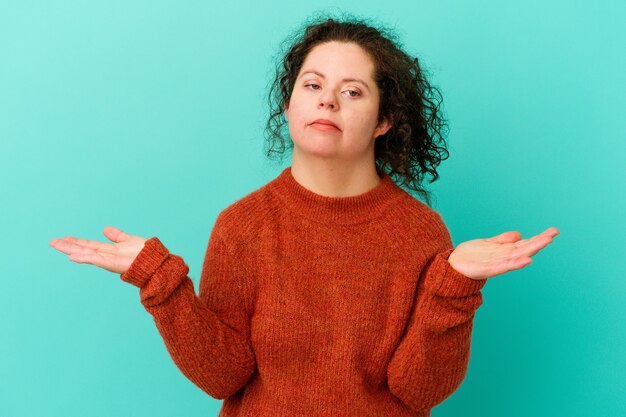 Vrouw met het syndroom van Down geïsoleerd twijfelende en schouderophalende schouders in vragend gebaar