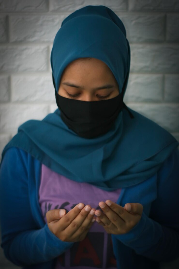Foto vrouw met hijab die tegen de muur bidt
