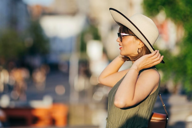 Vrouw met hoed wandelen in de stad op een zonnige dag