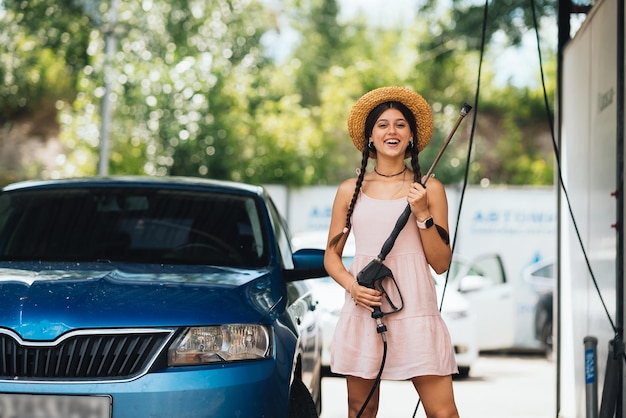 Vrouw met hogedrukslang bij wasstraat