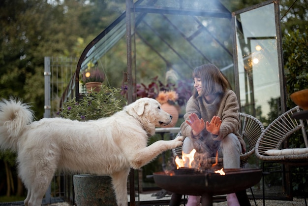Vrouw met hond bij het vuur in de achtertuin