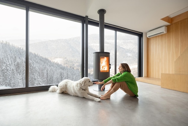 Vrouw met hond bij huis op de bergen in de winter