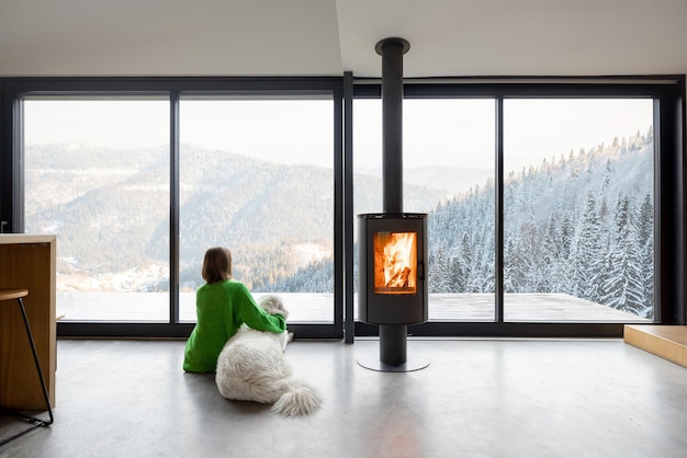 Vrouw met hond bij huis op de bergen in de winter