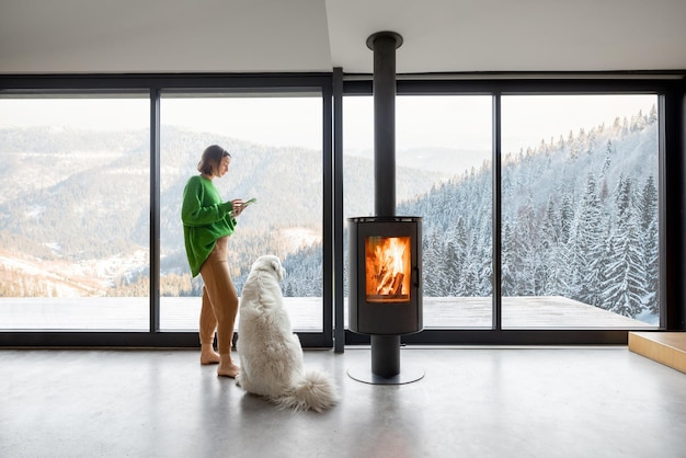 Vrouw met hond bij huis op de bergen in de winter