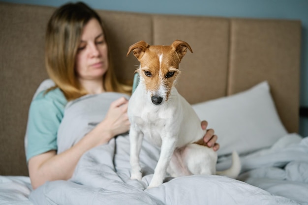 Vrouw met hond chillen op bed gebruik smartphone