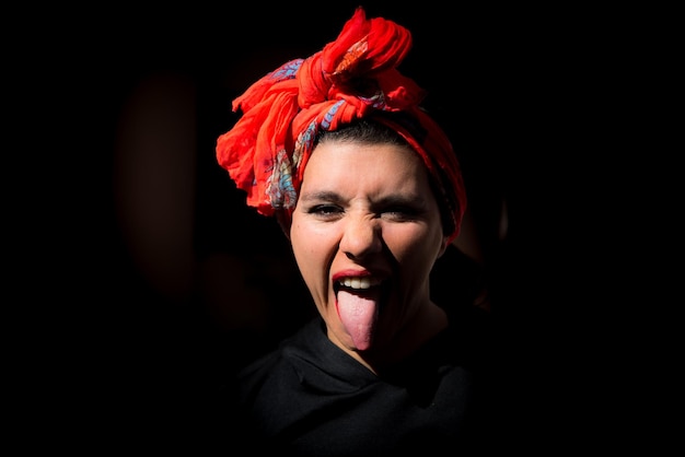 Vrouw met hoofddoek tong uit zwarte achtergrond