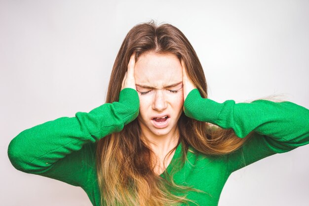 Vrouw met hoofdpijn die haar hoofd en boos houdt. Geschokt en overstuur uitdrukking. Hard werkconcept, brainstorm, veel zaken en banen