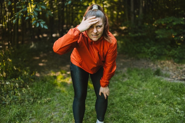 Vrouw met hoofdpijn tijdens het joggen Vrouw stopt met rennen omdat een hoofdpijn ernstige migraine veroorzaakt