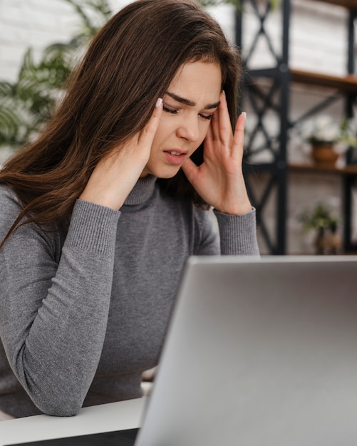 Vrouw met hoofdpijn tijdens het werken vanuit huis