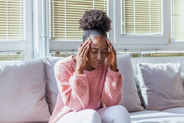 Vrouw met hoofdpijn zittend op de bank