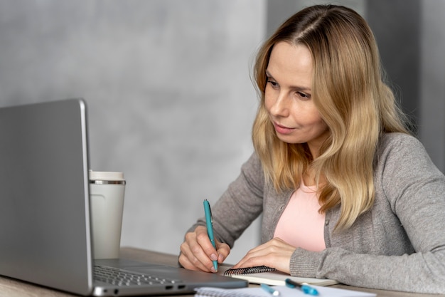 Foto vrouw met hoofdtelefoon die aan laptop werkt