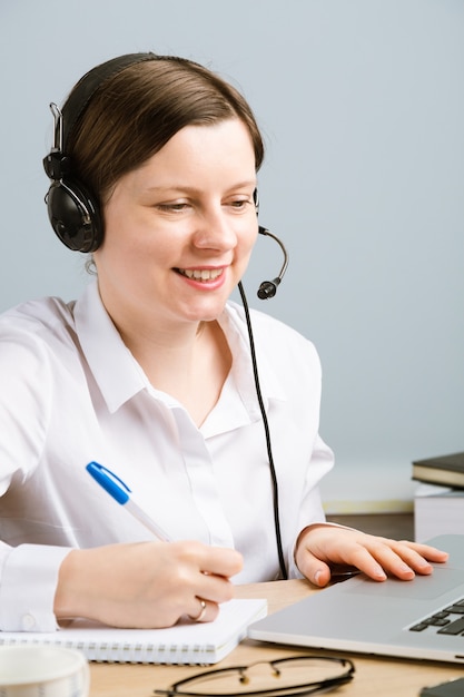 Vrouw met hoofdtelefoon die op kantoor werkt om problemen op te lossen. Callcentermedewerker die vanuit huis werkt.