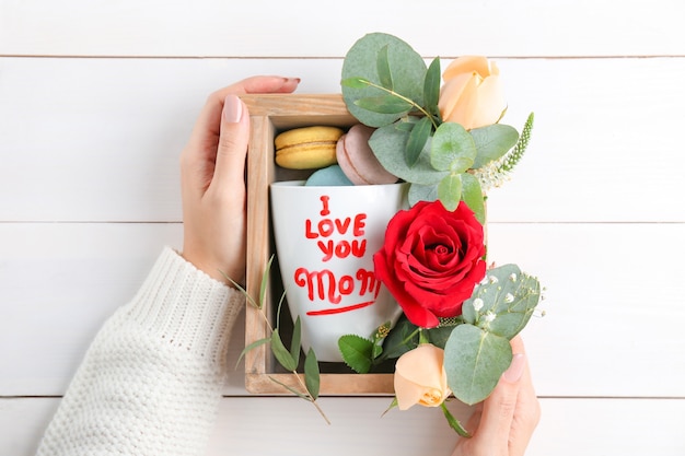 Vrouw met houten kist met geschenken voor moederdag op houten