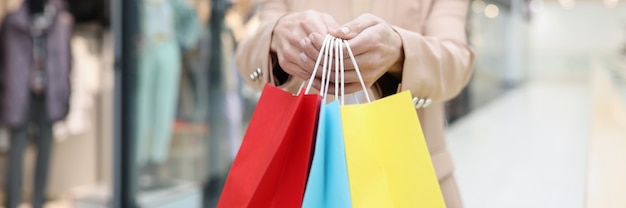 Vrouw met in handen veel veelkleurige papieren zakken met aankopen in de winkel close-up