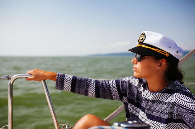 Foto vrouw met kapiteinshoed in boot op zee tegen de lucht