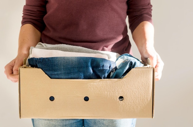 Vrouw met kartonnen doos met casual kleding voor alle seizoenen